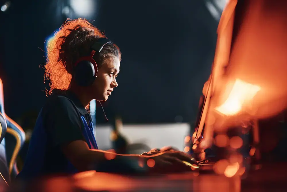 Woman wears headphones and plays a video game on a computer